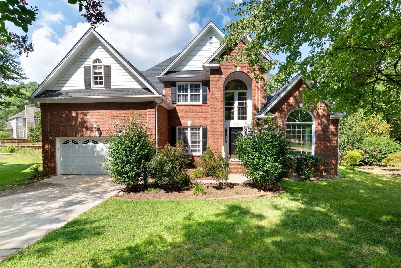 Two-story brick and siding home with a two-car garage and landscaped front yard