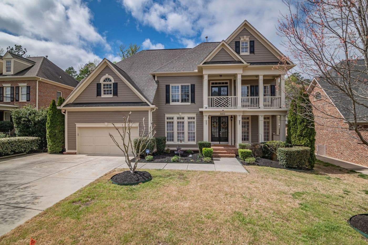 Tan brick two-story home with a second-floor balcony and a side-entry driveway