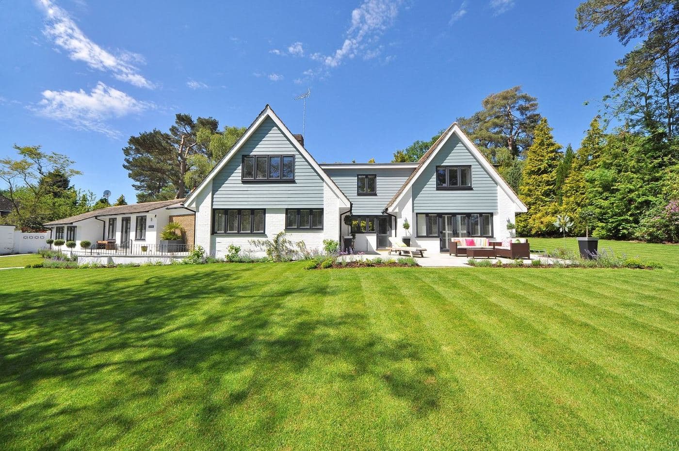 White modern farmhouse-style home set back on a wide, freshly mown lawn